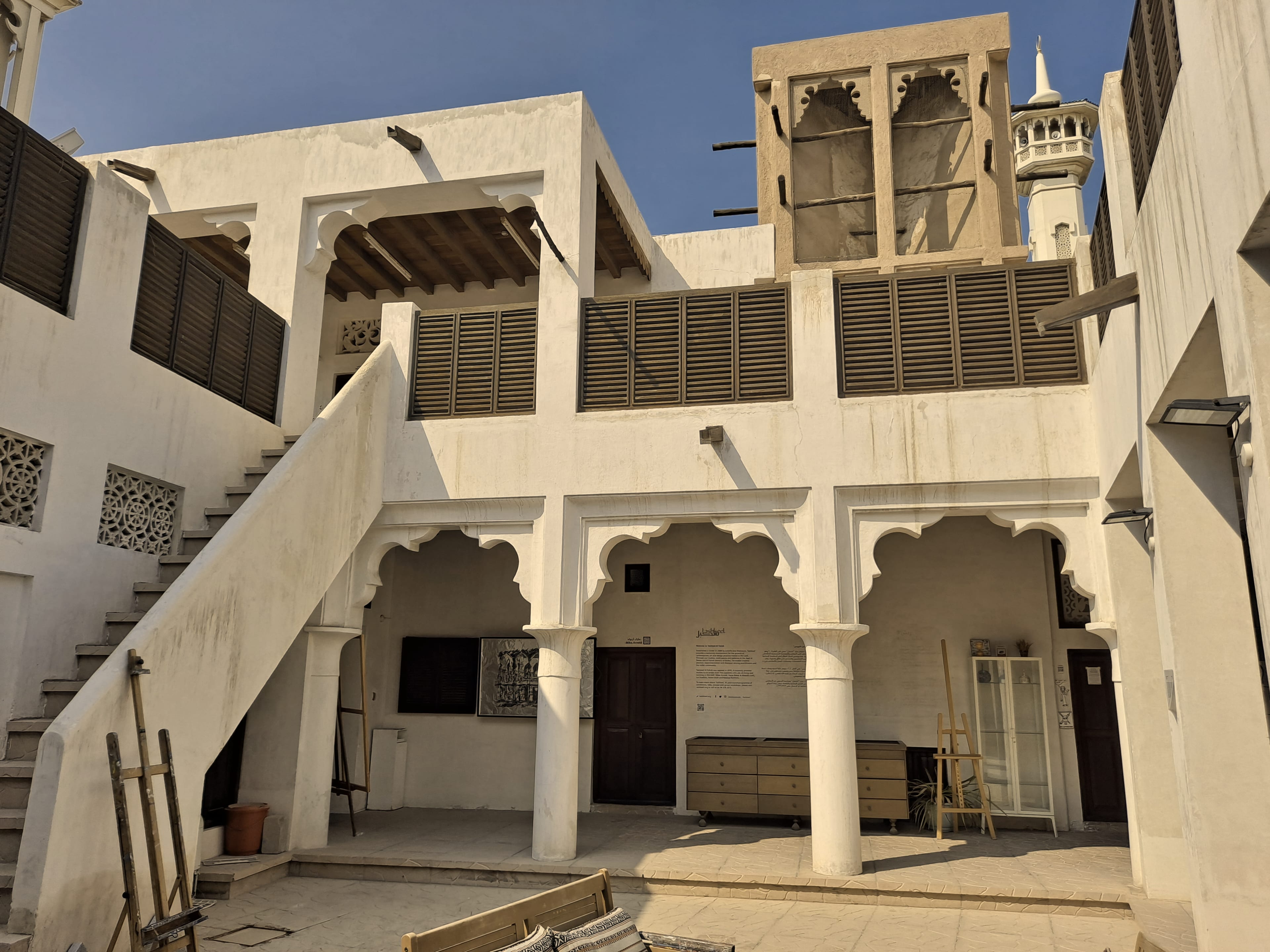 A whitewashed courtyard with arches and a wind tower in Al Bastakiya, Dubai